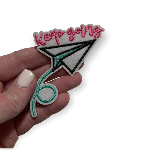 Paper airplane with “keep going” iron on patch